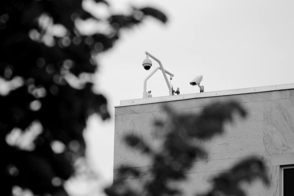 Black and white photo of security cameras on government building.
