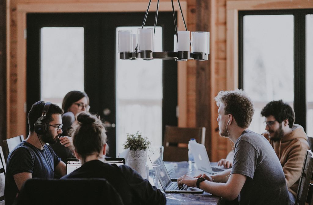 A group of people sitting and working at a table. 