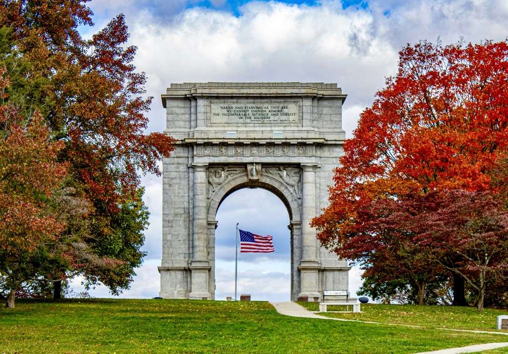 A monument with an American flag underneath it. 