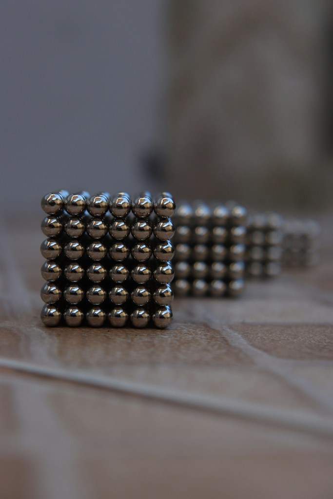 Silver beads on brown wooden table. 