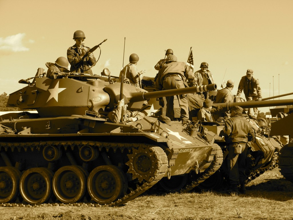 People sitting and standing on a battle tank. 