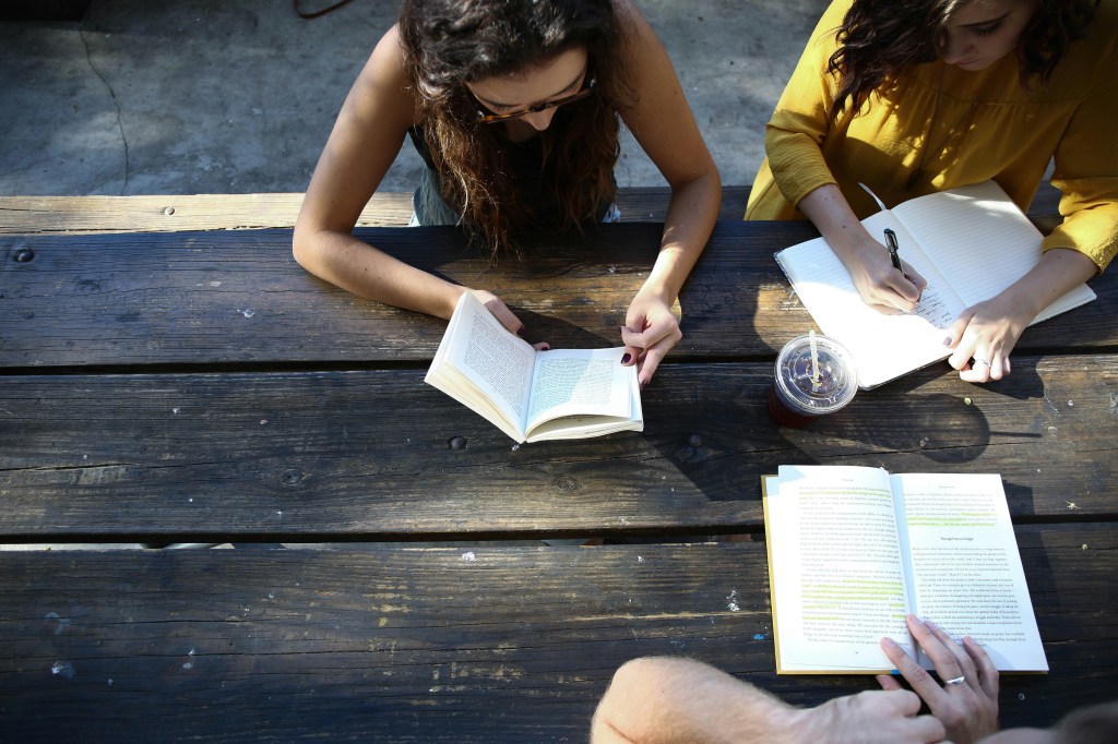 Woman reading book while sitting on chair. 