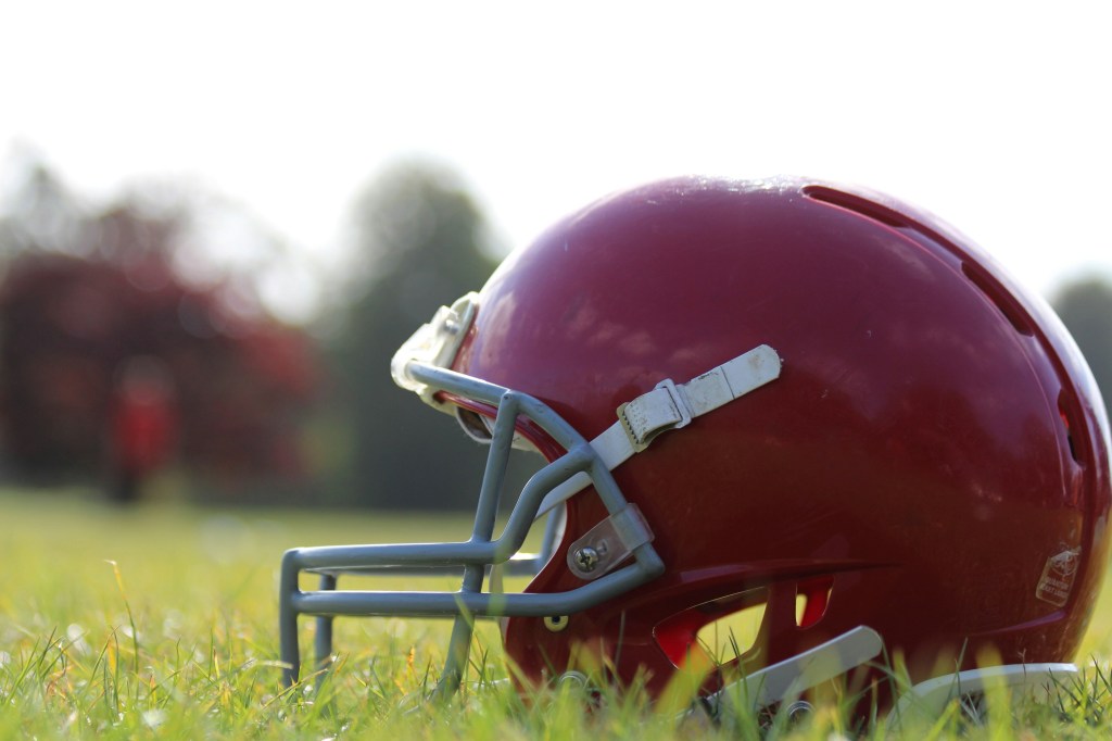 Red football helmet on green grass during daytime. 