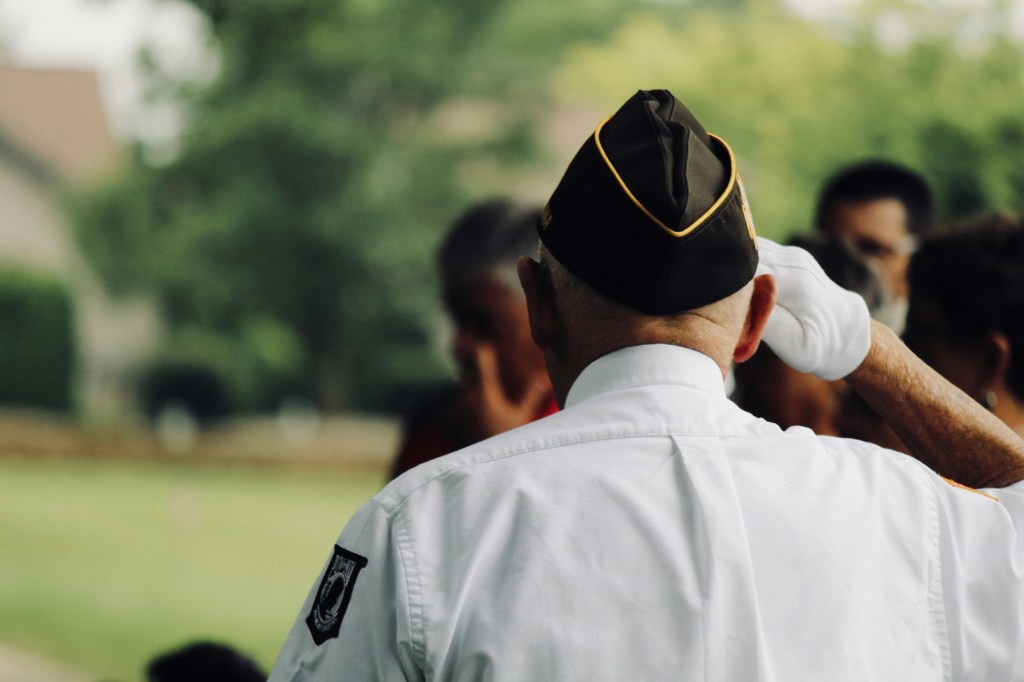 Man wearing white uniform saluting. 